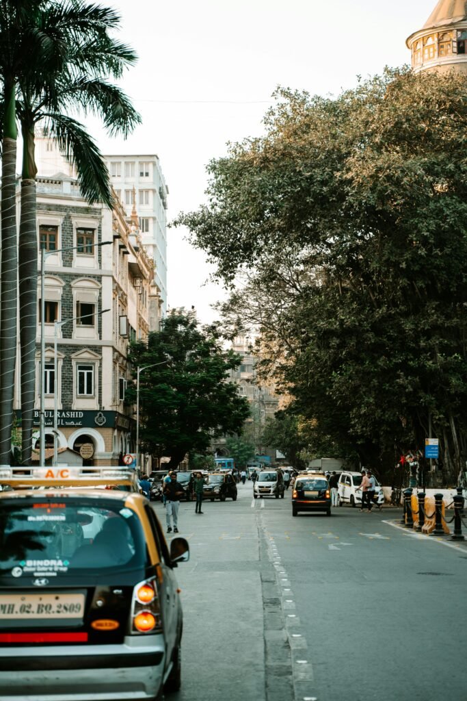 Vibrant city street view in Mumbai featuring taxis, palm trees, and historic architecture.