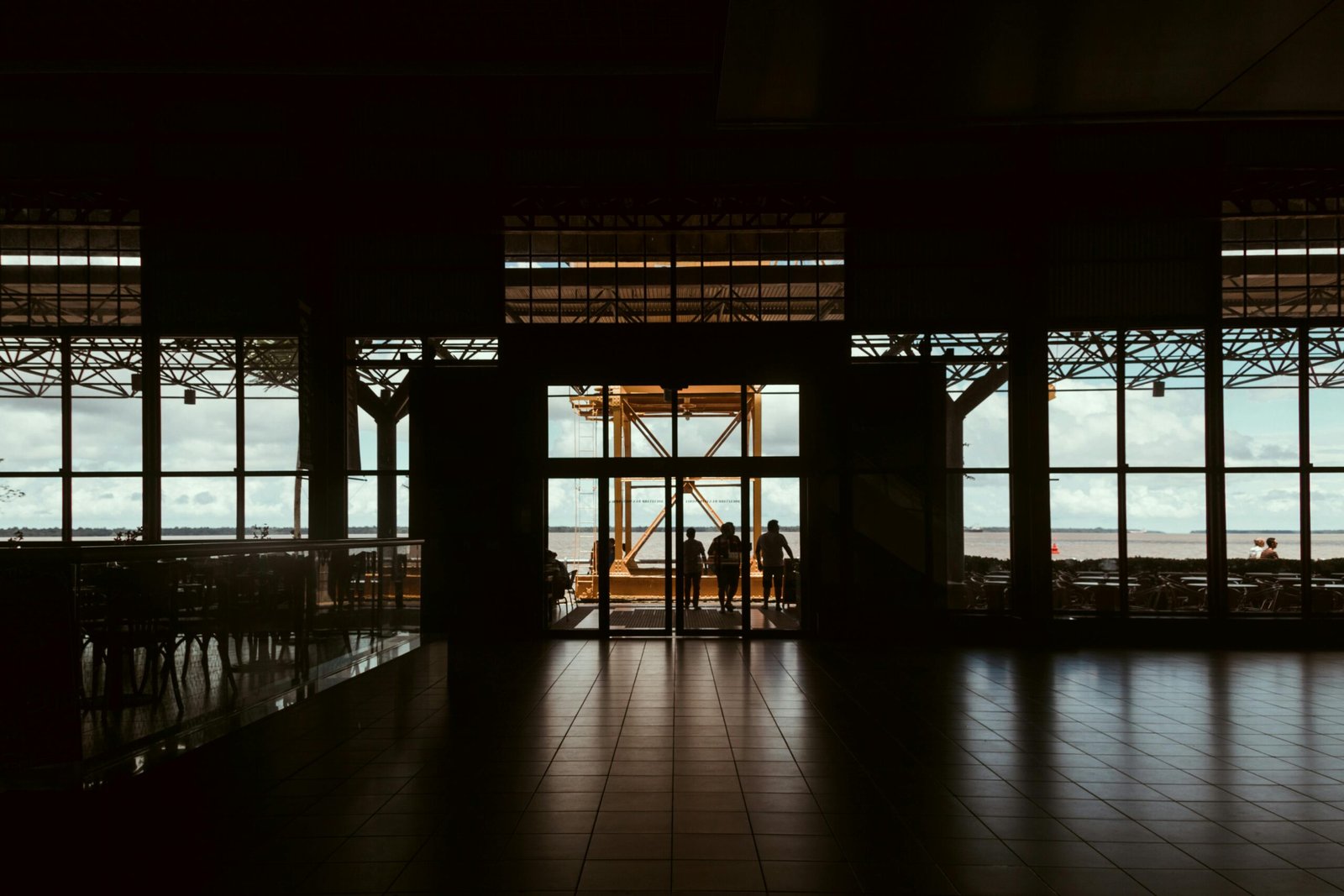 Silhouetted figures in a dark hallway leading to a bright outdoor view in Nazaré, Brazil.