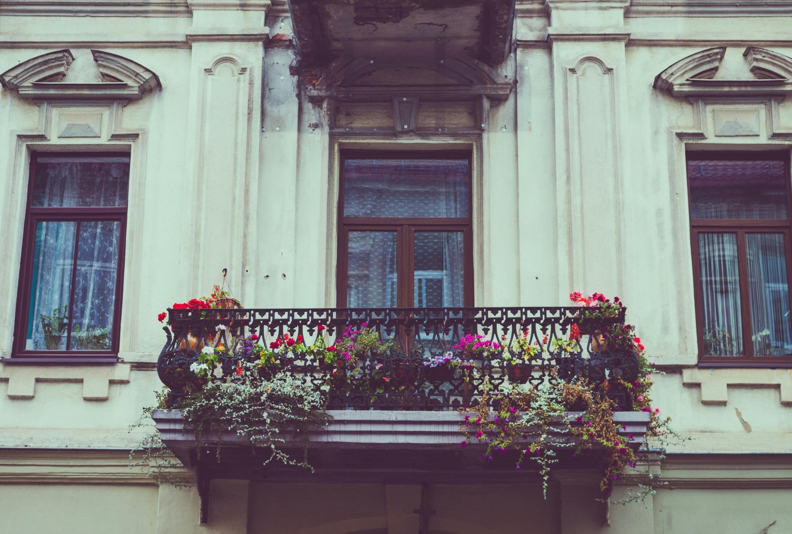 A beautiful vintage balcony adorned with colorful flowers and iron railing.