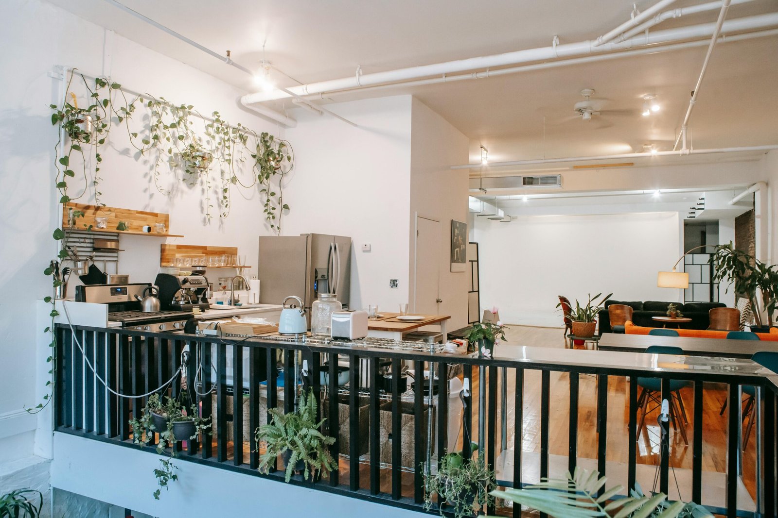 Upstairs interior of comfortable home in Scandinavian style with kitchen and lounge zone decorated with potted plants and lamps hanging around